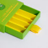 Green drawer-style pre-roll box with five yellow compartments and ribbon pull