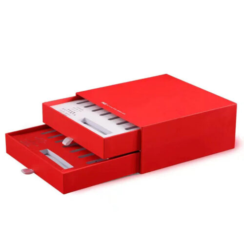 Red two-drawer skincare gift box partially open with fitted ampoule inserts and ribbon pull tabs Red two-drawer skincare gift box partially open with fitted ampoule inserts and ribbon pull tabs