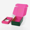 Caja de cartón ondulado verde y rosa para enviar café por correo, con inserto