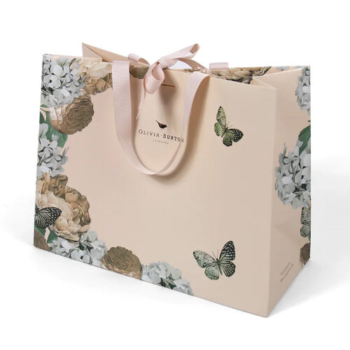 Hand holding blush paper gift bag Hand holding blush paper gift bag