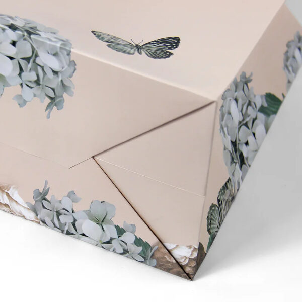 Hand holding blush paper gift bag